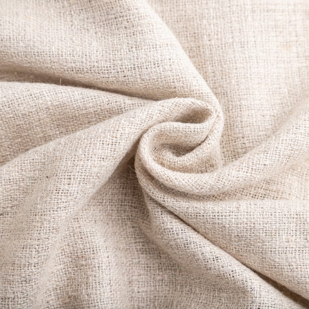 Close-up image of beige plain weave cotton fabric, showing its soft texture and fine weave pattern with slight wrinkles.