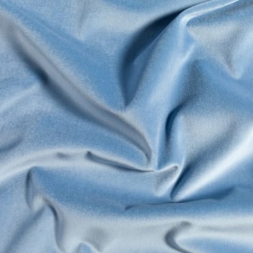 Close-up of light blue polyester velvet fabric with a smooth, shiny, and plush surface.