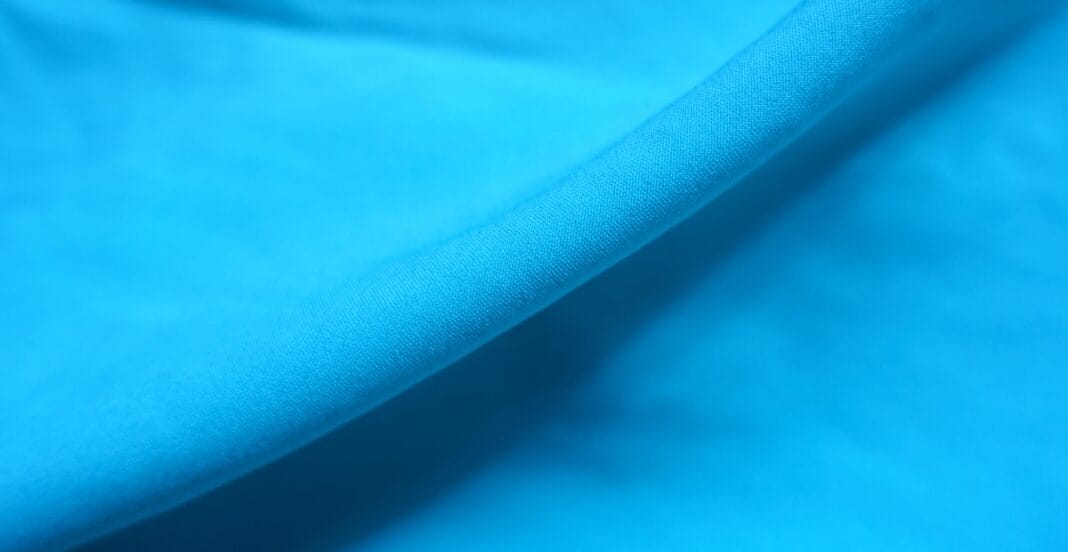 Close-up image of smooth, lightweight blue polyester chiffon fabric with a delicate, semi-transparent texture and fine weave.
