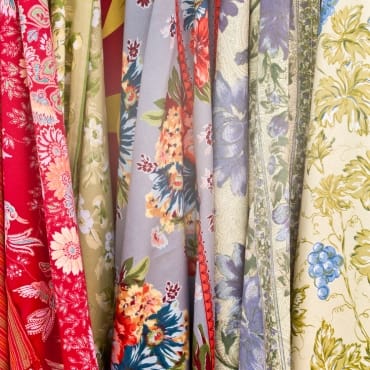 A variety of colorful printed chiffon fabrics with floral and botanical patterns in vibrant shades.