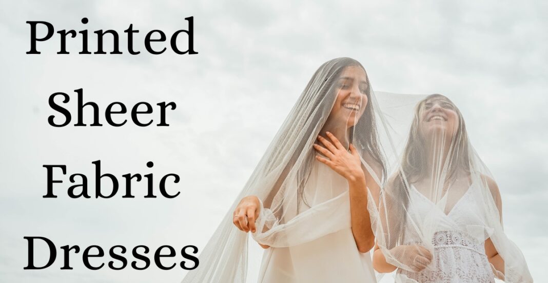 Two women wearing sheer fabric dresses, smiling and looking up, with one of them holding a sheer veil over her head against a cloudy sky background.