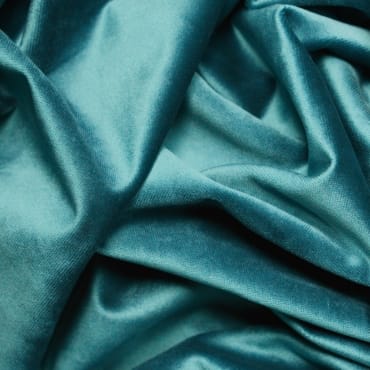 Close-up of deep teal rayon velvet fabric with a smooth, shiny, and plush surface.