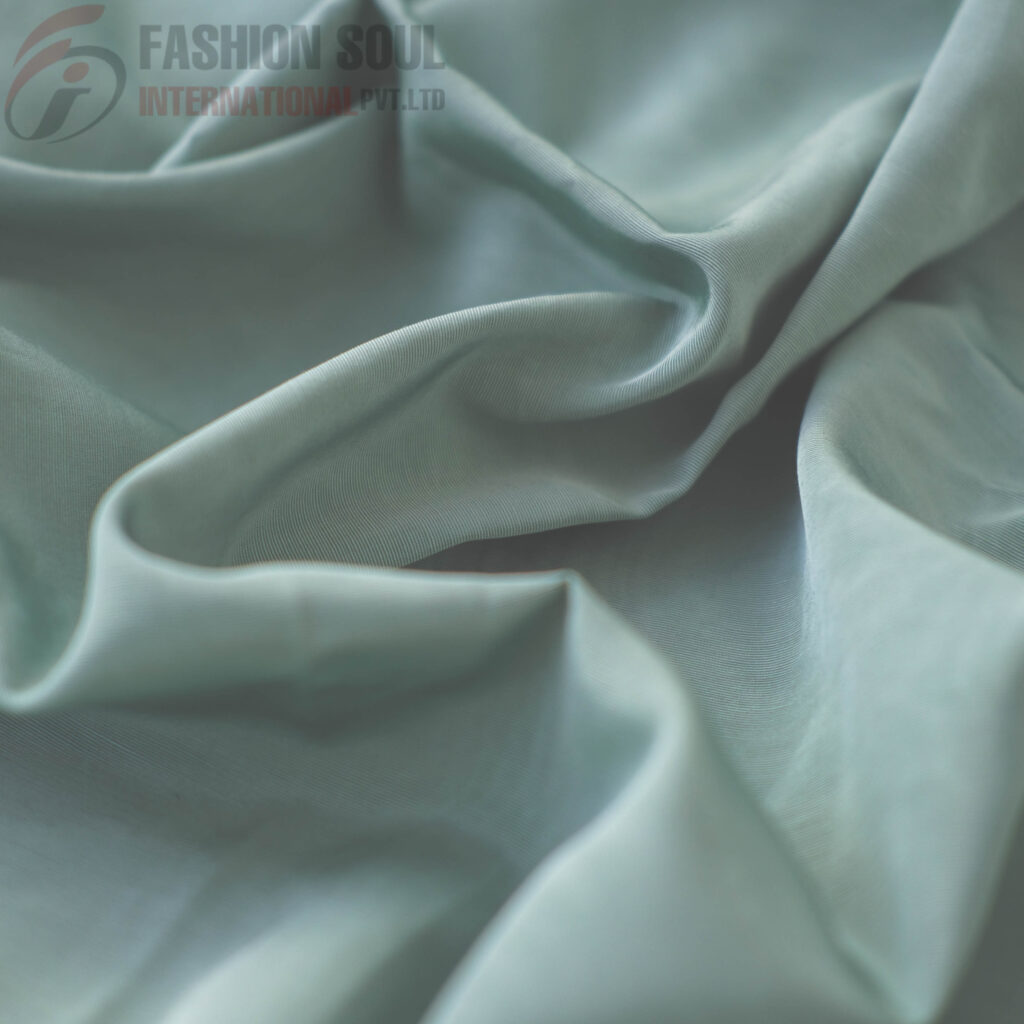 Soft, smooth, light-colored fabric with gentle folds and a slightly shiny surface.
