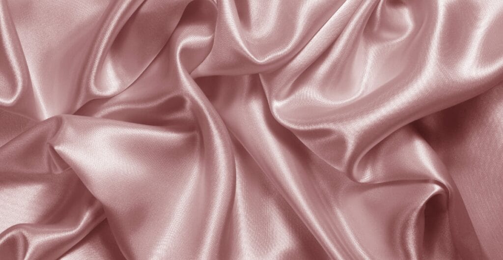 Smooth, shiny draped pink satin spandex fabric with soft folds and sheen.