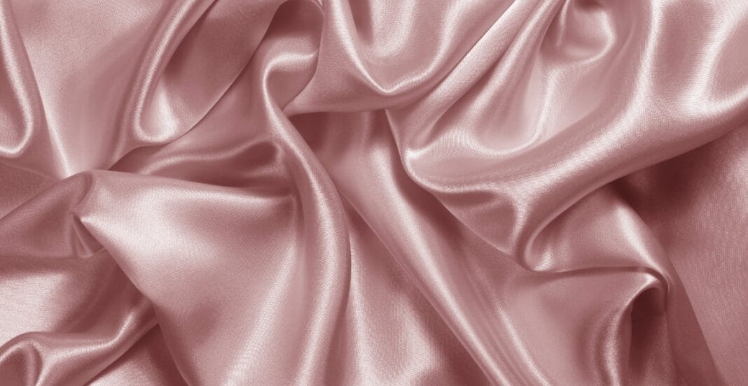 Smooth, shiny draped pink satin spandex fabric with soft folds and sheen.