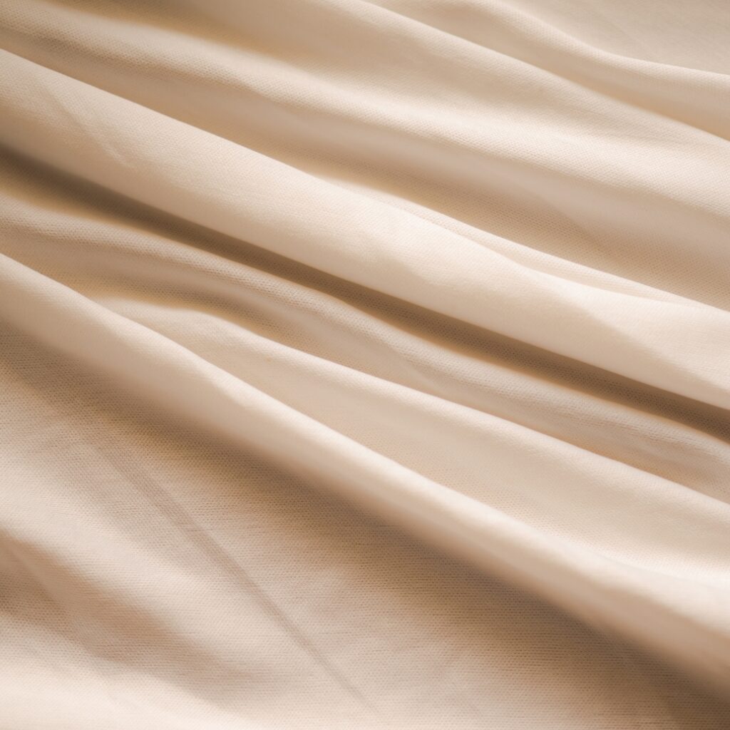 Close-up image of smooth, cream-colored fabric with gentle folds.