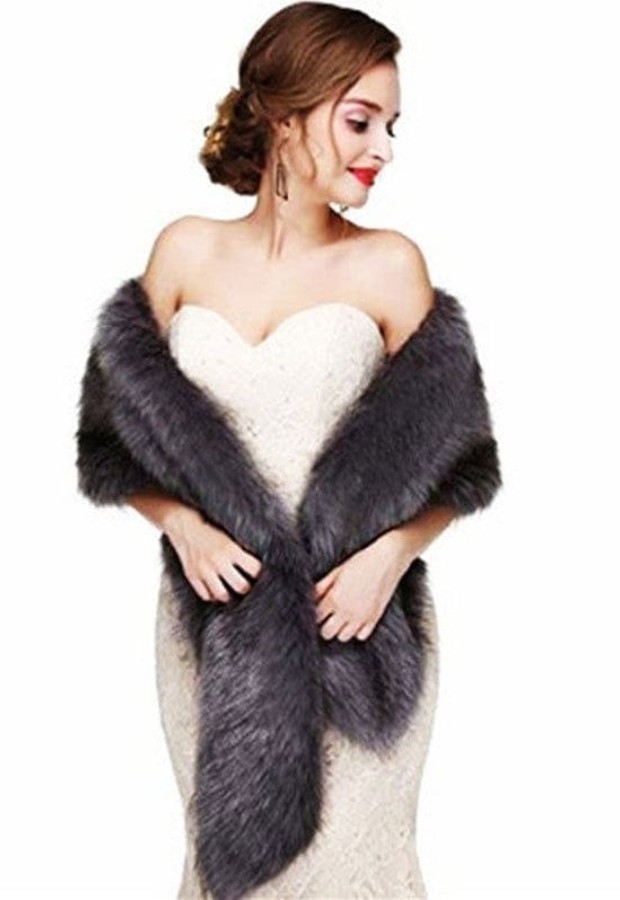Elegant woman in a strapless white lace dress, draped in a luxurious dark gray fur stole or wrap, styled against a plain white background.
