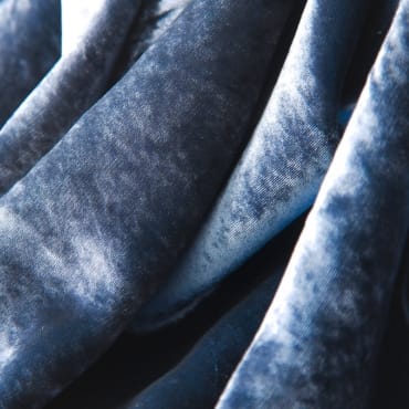 Close-up of stretched velvet fabric in a dark blue shade, showing its smooth and slightly shiny surface.