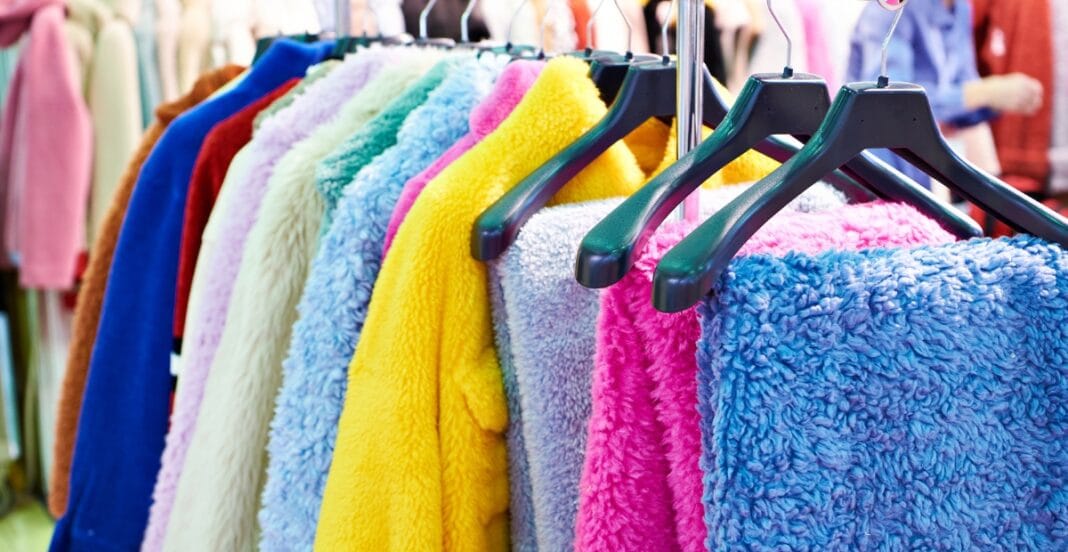 Colorful display of plush terry cloth garments hanging on black hangers at a retail store.
