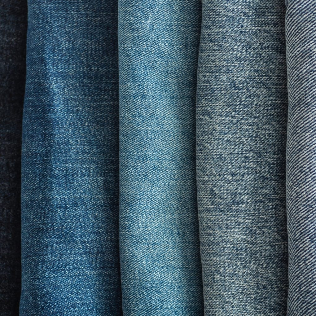 Close-up image of denim chambray fabric showing various shades of blue and detailed weave patterns.