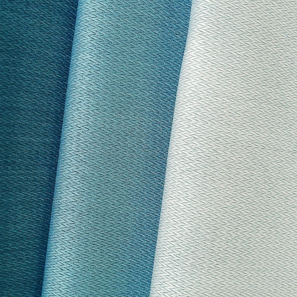 Close-up image of three fabric rolls in shades of blue, showcasing a lightweight, sheer, and textured material with a delicate, crisscross weave pattern.