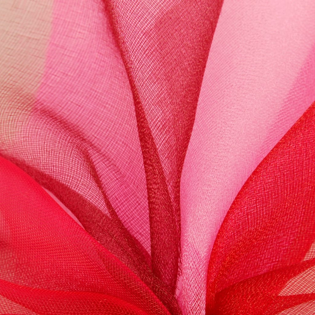 Close-up image of layered, semi-transparent polka-dotted red, pink, and beige organza fabric with a sheer, delicate texture.