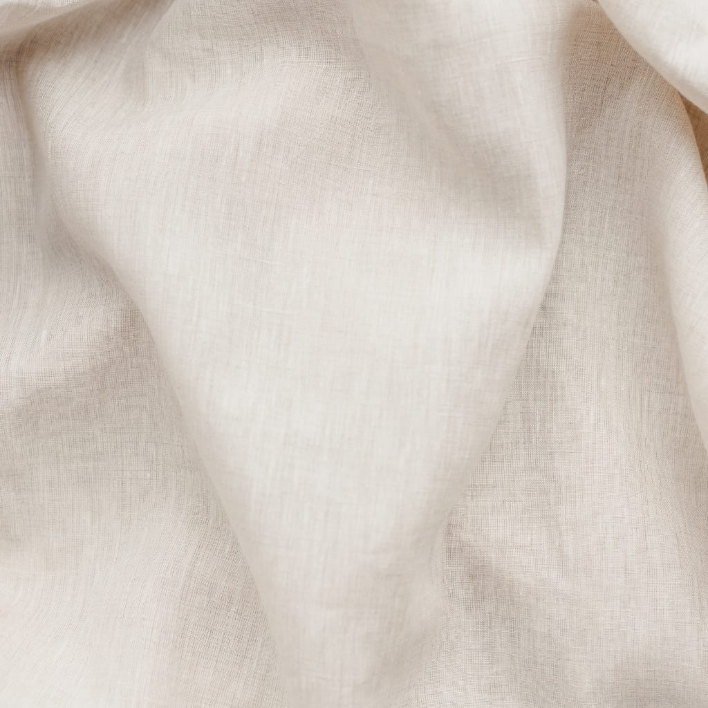 A close-up of soft, light beige fabric with gentle folds and a smooth, textured surface.