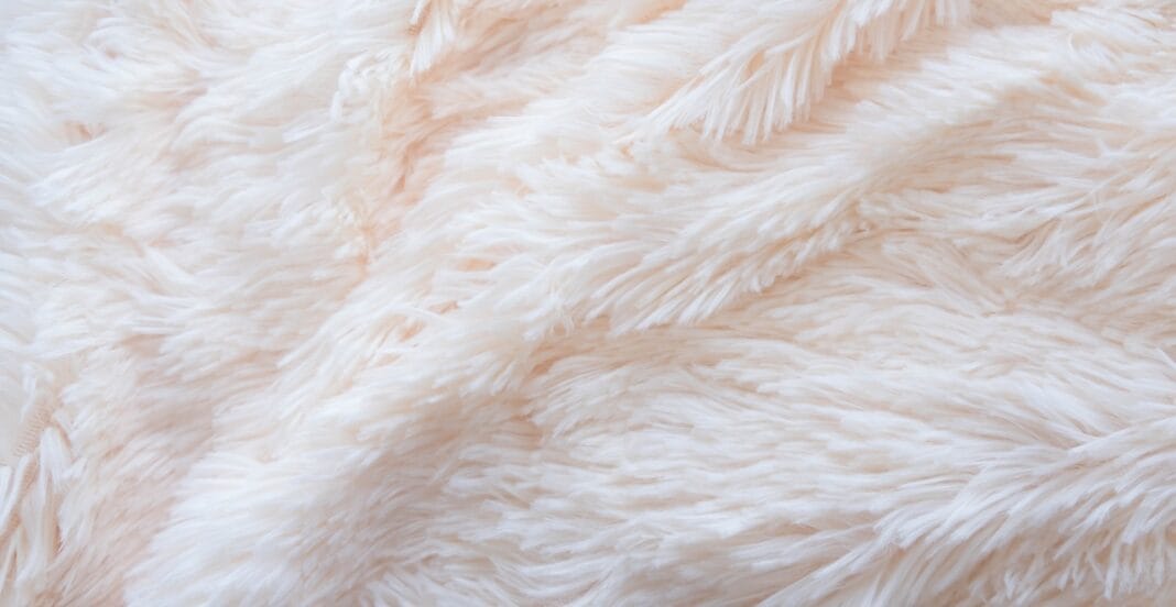 Close-up image of soft, fluffy, light pink fuzzy fabric with a textured, feather-like surface.