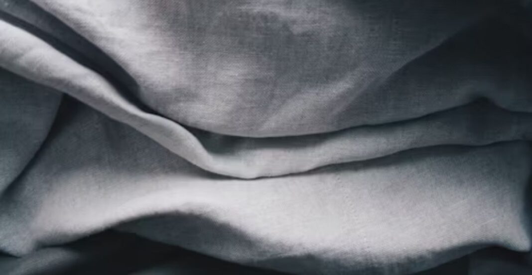 Close-up of wrinkled gray linen fabric with soft folds and shadows.