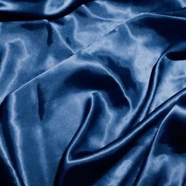 Close-up image of deep blue velvet spandex fabric with soft folds and a shiny, luxurious surface.