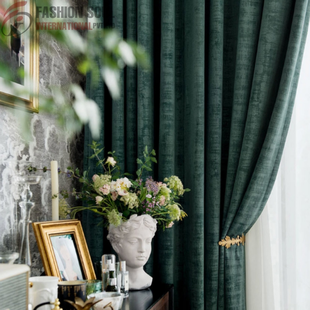 A close-up of a decorative arrangement on a dark surface, featuring a white bust planter with a large floral arrangement, a small framed photo, and glass candle holders. In the background, dark green curtains are partially pulled aside, revealing a white window.