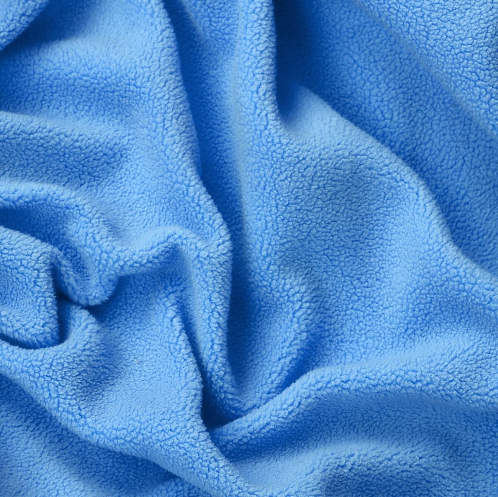 Close-up image of bright blue fleece fabric with a soft, textured surface and gentle folds.