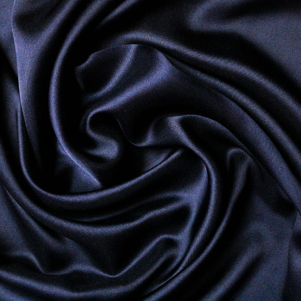 A close-up view of smooth, shiny black satin fabric with soft folds and gentle sheen.