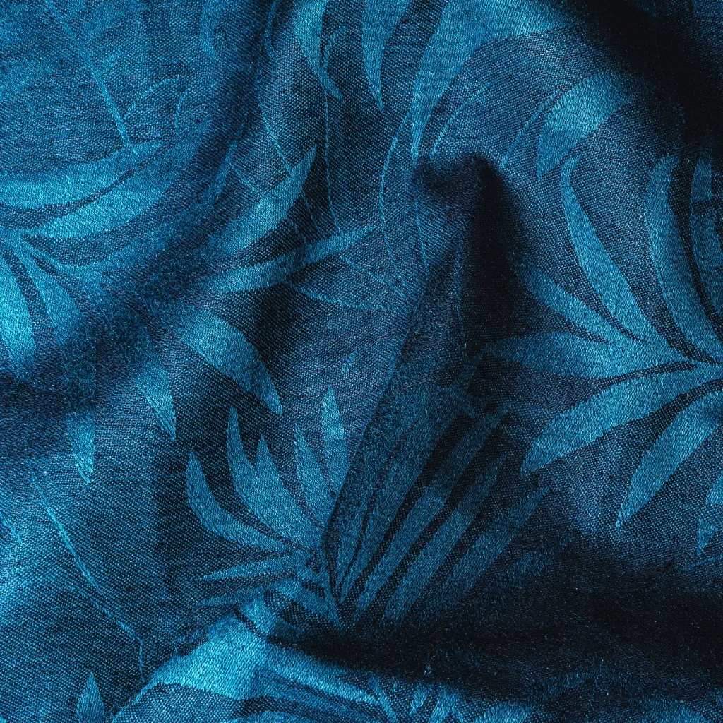 A close-up image of blue island cotton fabric with a textured surface and a leaf pattern.