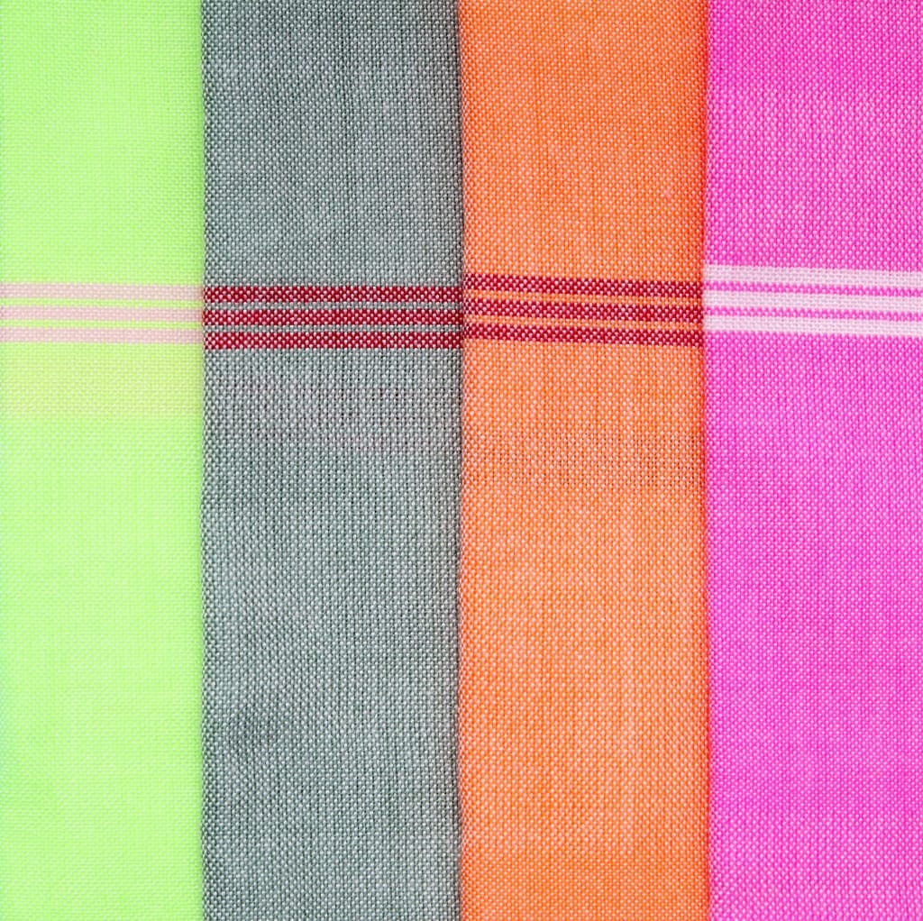 Close-up image of four pieces of fabric in neon green, gray, orange, and pink, all with a textured, coarse surface.