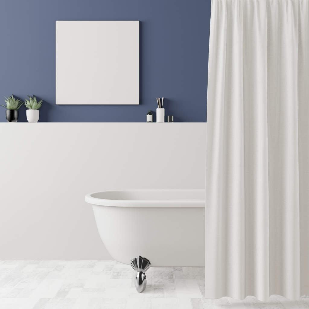 Modern bathroom interior with a white clawfoot bathtub, cream-colored satin curtain, dark blue wall, white shelf with decorative items, and a blank white canvas.