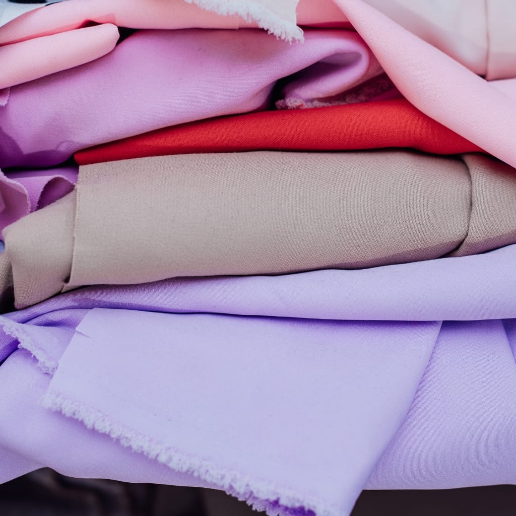 Folded and layered fabric pieces in various shades of pink, purple, and cream.