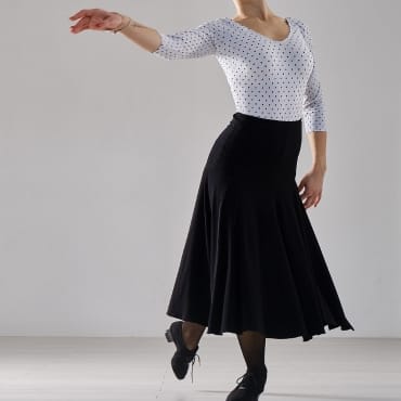 Performer dancing in a white top and black skirt, showcasing elegance and flexibility.