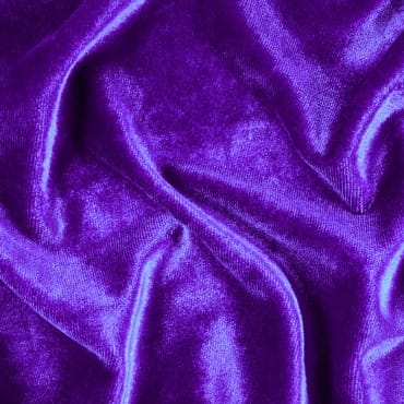 Close-up of vibrant purple velvet fabric with soft, flowing folds, showcasing its rich texture and sheen.