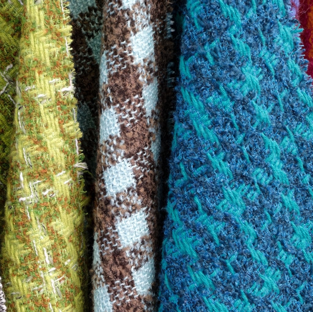 Close-up image of a basket weave cotton fabric showcasing three different textured and colored woven textiles: bright yellow-green on the left, brown and white checkered in the middle, and vibrant blue on the right.