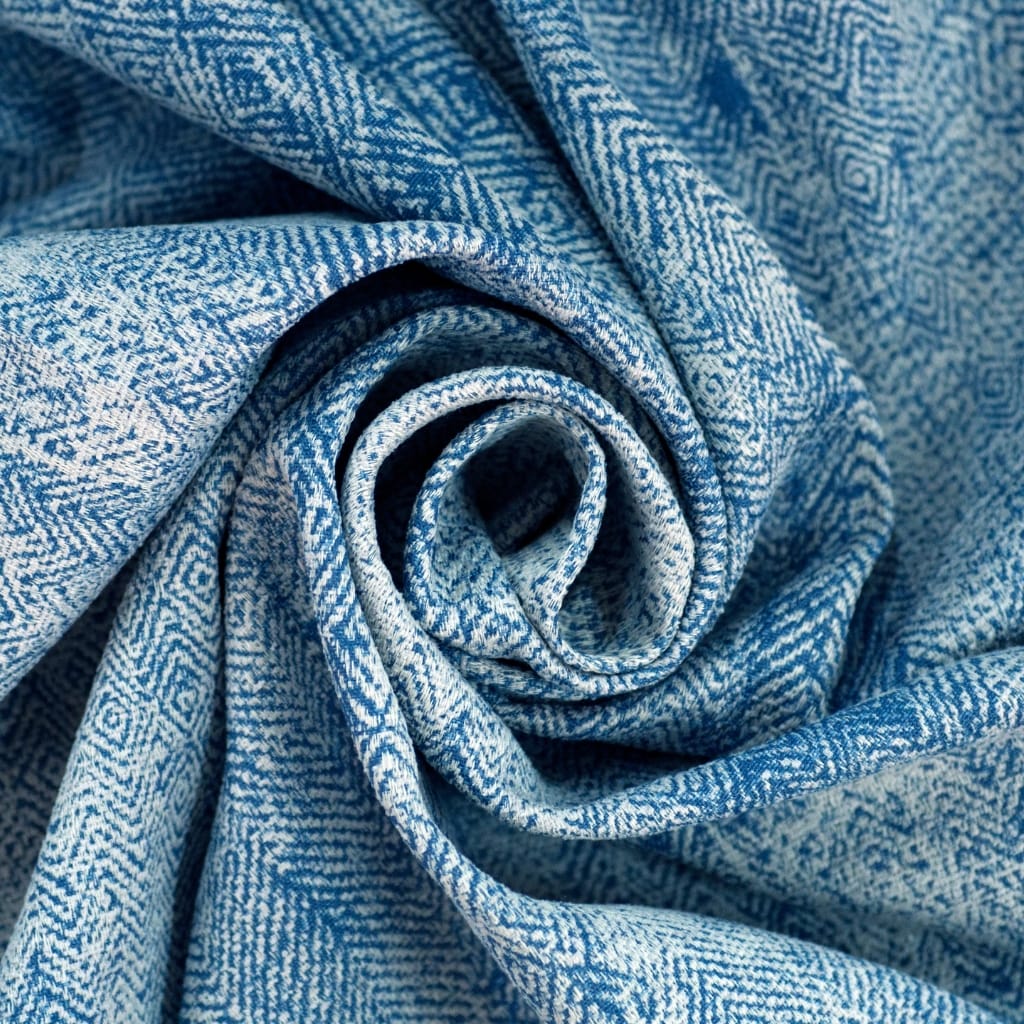A close-up image of a folded piece of chambray fabric, showcasing its soft texture and intricate weave pattern in shades of blue and white.