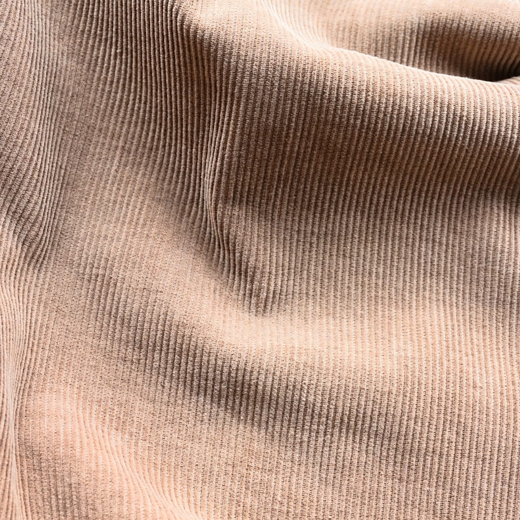 A close-up image of peach-colored corduroy fabric showing its distinctive narrow, parallel ridges (wales) and soft texture.