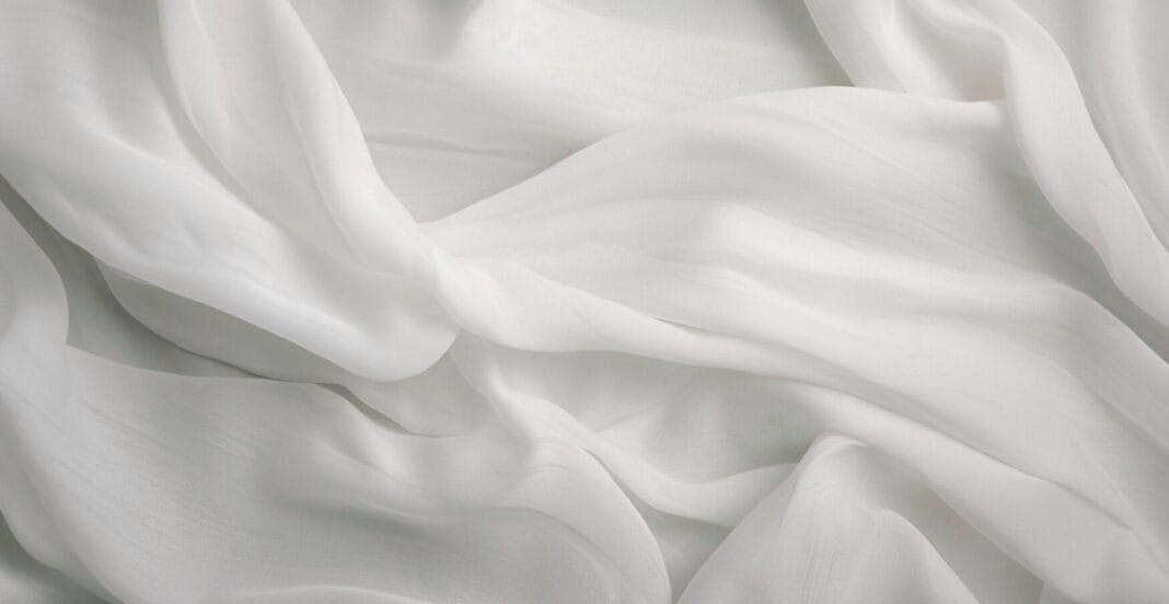 Close-up image of soft, flowing white chiffon fabric with gentle folds and a delicate, lightweight appearance.