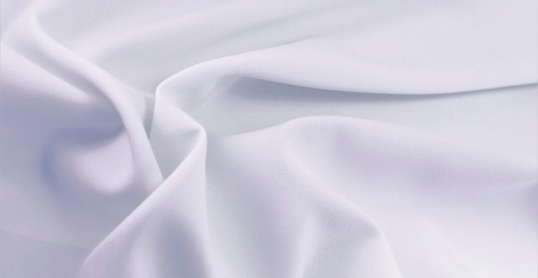 A close-up image of smooth, white Cupro fabric with soft folds and a subtle sheen.