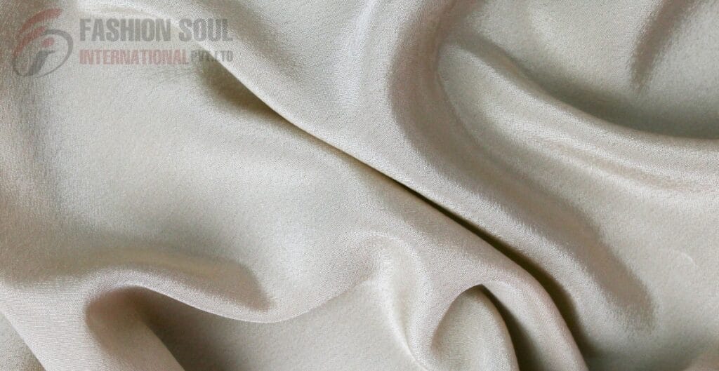 Close-up of silky, creamy-white fabric with smooth folds and a lustrous sheen.