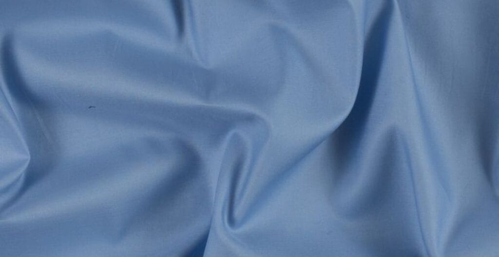 Close-up image of smooth, light blue Egyptian cotton fabric with gentle folds.
