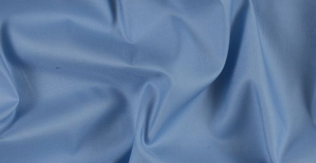 Close-up image of smooth, light blue Egyptian cotton fabric with gentle folds.