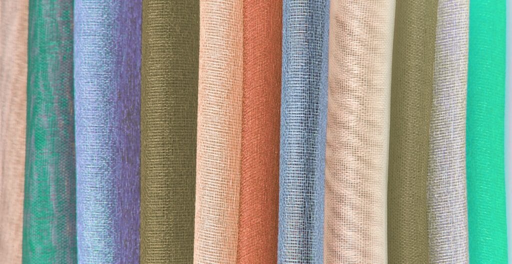 Close-up image of multiple rolls of nylon organza fabric in various colors, showcasing the sheer and lightweight texture.