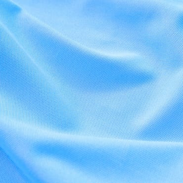Close-up image of light blue polyester-spandex fabric with a smooth, slightly textured surface and soft folds.