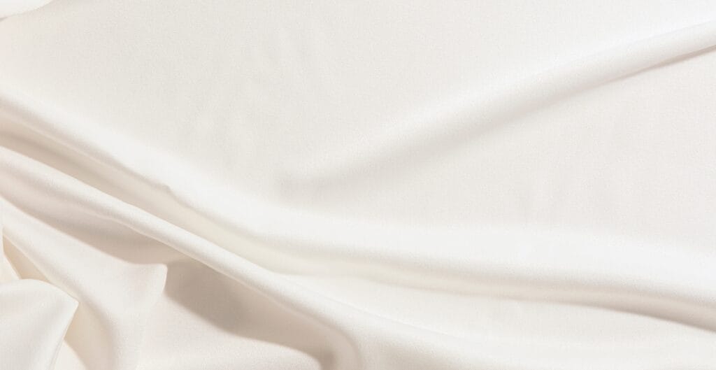 A close-up image of smooth, luxurious, and soft premium cotton fabric with gentle folds and a silky sheen.