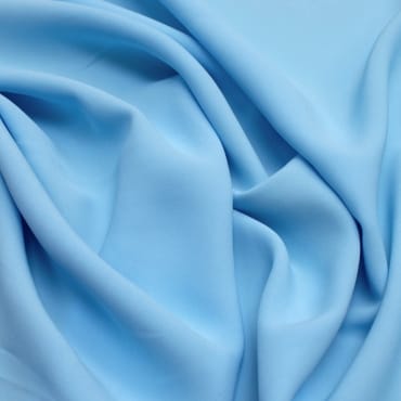 Close-up image of light blue rayon spandex fabric with soft folds and a smooth texture.