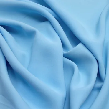 Close-up image of light blue rayon spandex fabric with soft folds and a smooth texture.