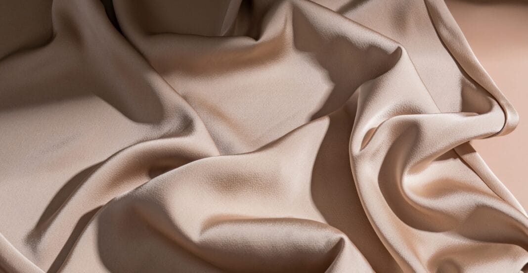 Close-up image of smooth, luxurious satin chiffon fabric with gentle folds and a soft sheen.