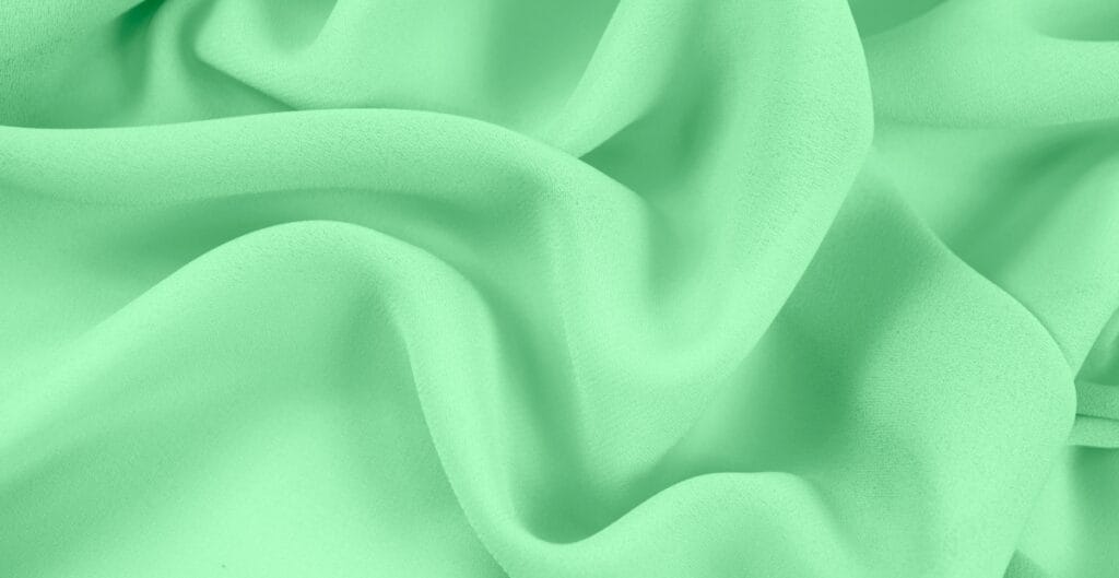 Close-up image of light green chiffon fabric with soft folds and sheer texture.