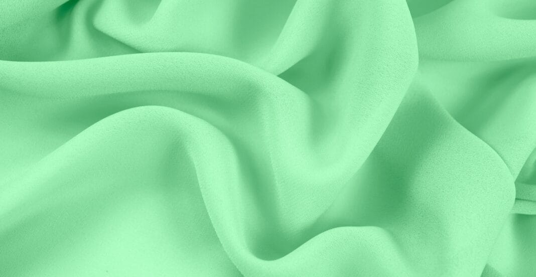 Close-up image of light green chiffon fabric with soft folds and sheer texture.