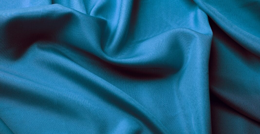 Close-up image of blue spandex fabric with visible texture and wrinkles.