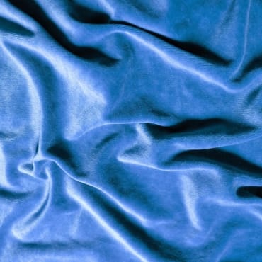 Close-up of smooth, rich blue velvet fabric with soft folds and a luxurious sheen.