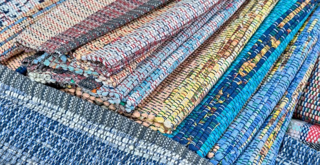 A variety of colorful woven fabric rolls, showcasing the texture and intricate weaving patterns typical of cotton weave fabric used in fashion.