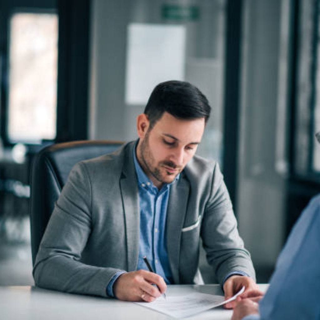Businessman signing a document during a formal meeting in a modern office.