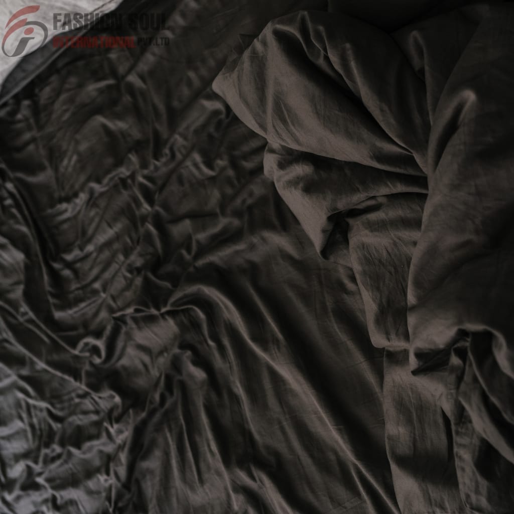 A close-up of black, shiny, and wrinkled fabric, showing texture and folds.